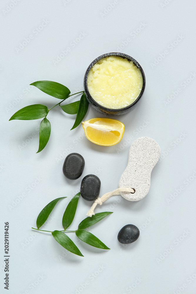 Obraz premium Bowl of lemon body scrub with massage brush and spa stones on grey background