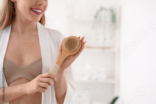 Fotografie Young woman with anti-cellulite brush in bathroom, closeup