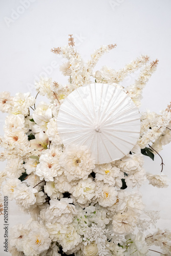 Detail with white japanese vibe umbrela, Elegant white flowers cascade upward in graceful tiers. Delicate blooms and soft petals frame a clean, minimalist backdrop. Neutral tones enhance purity