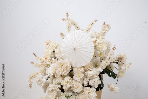 Detail with white japanese vibe umbrela, Elegant white flowers cascade upward in graceful tiers. Delicate blooms and soft petals frame a clean, minimalist backdrop. Neutral tones enhance purity