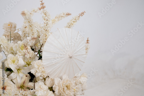 Detail with white japanese vibe umbrela, Elegant white flowers cascade upward in graceful tiers. Delicate blooms and soft petals frame a clean, minimalist backdrop. Neutral tones enhance purity