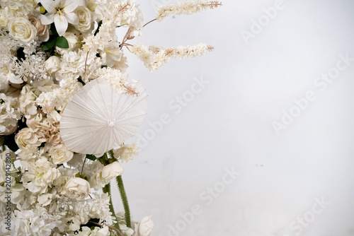 Detail with white japanese vibe umbrela, Elegant white flowers cascade upward in graceful tiers. Delicate blooms and soft petals frame a clean, minimalist backdrop. Neutral tones enhance purity