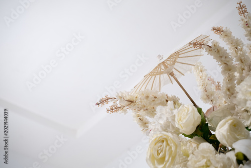 Detail with white japanese vibe umbrela, Elegant white flowers cascade upward in graceful tiers. Delicate blooms and soft petals frame a clean, minimalist backdrop. Neutral tones enhance purity