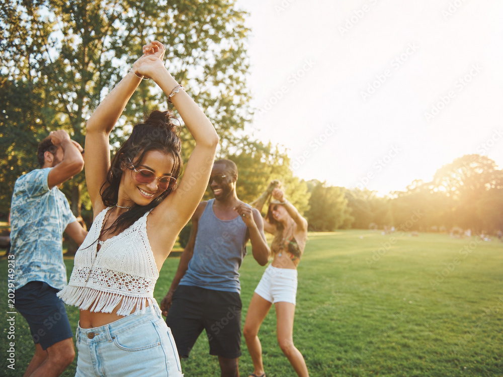 Obraz premium Festivalgoers Dancing in a Sunlit Park with Joyful Summer Energy