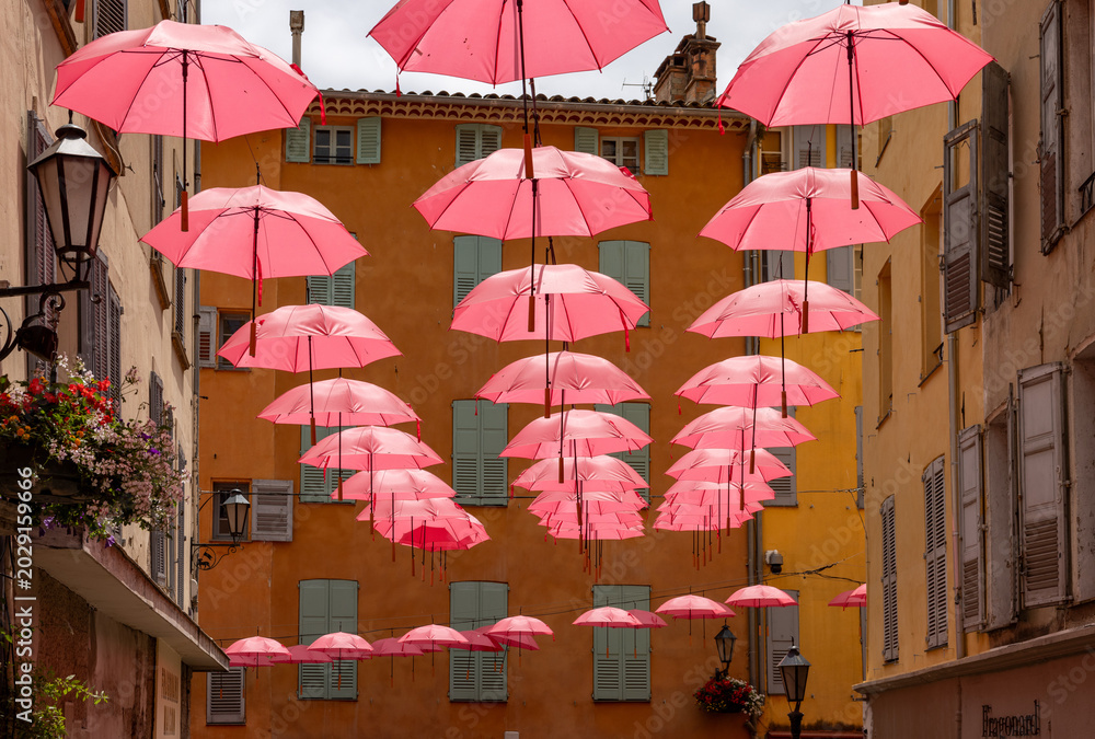 Obraz premium Streets of Grasse, a city known for its perfumery, decorated with pink umbrellas on the occasion of the annual international exhibition of roses - Expo Rose.