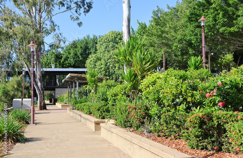Foto Landscaped pedestrian walkway with lush tropical gardens and historic-style lamp