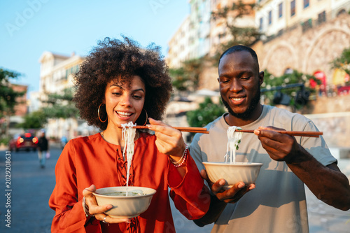 Cuadro en lienzo Young travelers relaxing with authentic street food, discovering new cultures an