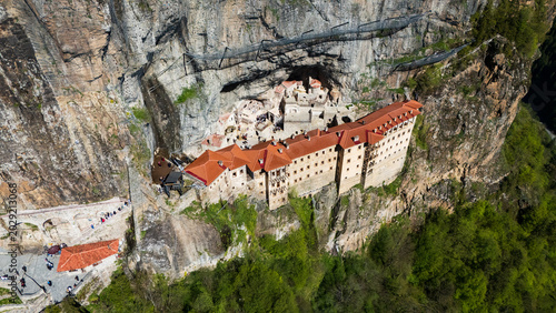 Breathtaking top-down drone perspective of the historic Greek Orthodox Sumela Monastery nestled among dense green pine woods in Trabzon, Turkey