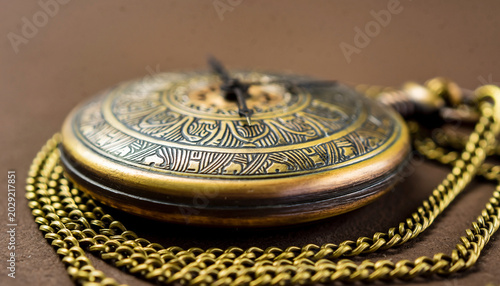 Close-up of an antique pocket watch with chain on a flat surface.