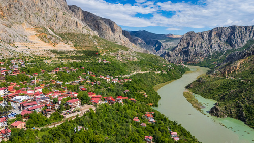 Aerial panoramic view of Kemaliye town in Erzincan, Turkey. Scenic drone shot of traditional houses with red roofs terraced on steep mountain slopes above the winding Karasu River