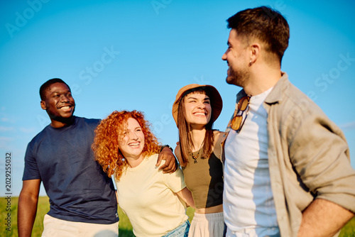 Schilderij op canvas Group of diverse young adult friends smiling and laughing together outdoors unde