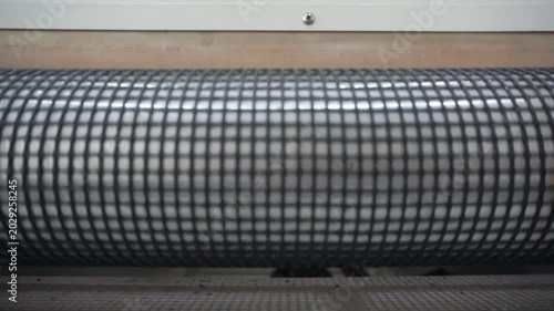 Machine's conveyor distinct grid pattern rotating, showcasing the intricate mesh texture on production machinery, Still shot