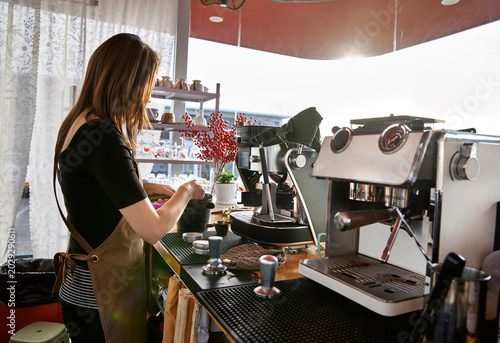 Tableau sur toile A female barista at a coffee shop is making espresso.