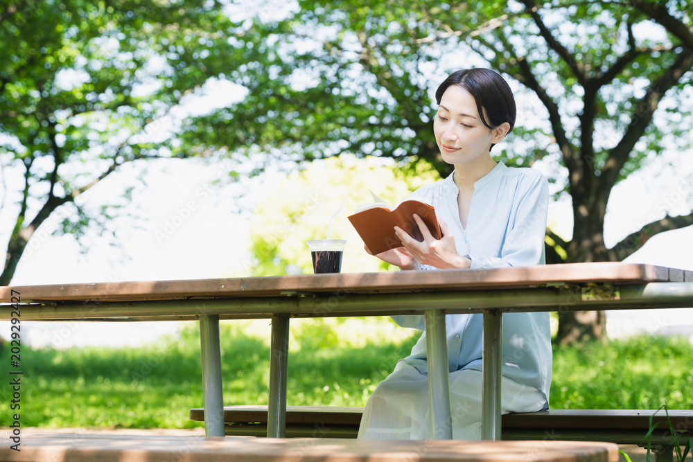 Fototapeta premium 屋外で読書をする若い女性 ライフスタイルイメージ