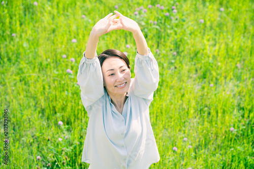 Fotografie 草原でストレッチをする若い女性　ライフスタイルイメージ