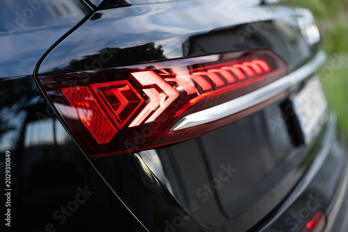 Rear LED lights closeup of electric SUV, stylish exterior design of car. Headlight, taillight, car, brake, indicator, led, light. Close up detail on one of the LED red taillight modern crossover car