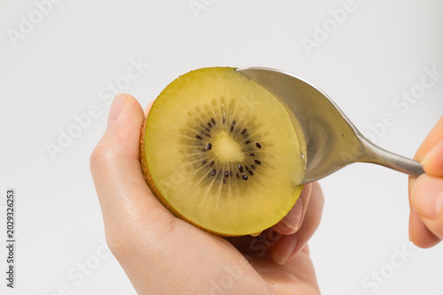 Eating Fresh Golden Kiwi with Spoon Close Up on White Background
