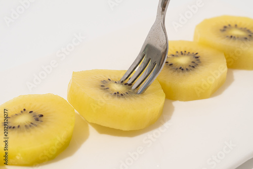 Fresh Golden Kiwi Slices with Fork on White Plate – Healthy Fruit Snack Close Up