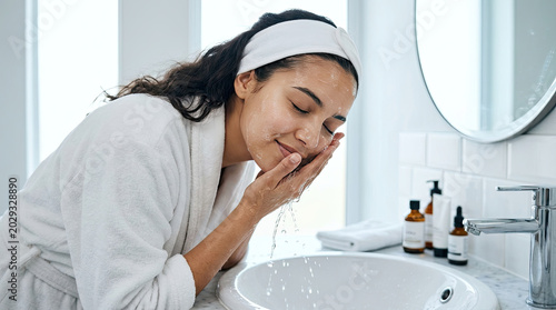 Woman washing her face with soap and water in a clean bathroom