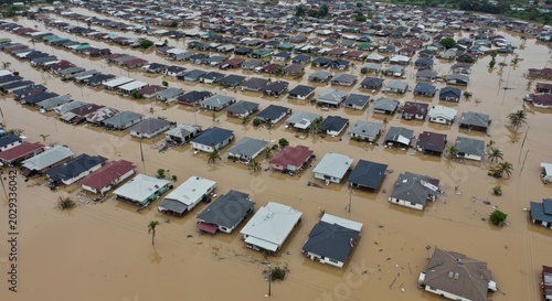 Wide drone shot showing rows of houses in a vast suburban area completely surrounded by floodwater.