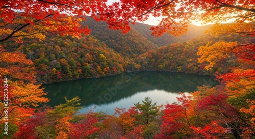 Wide mountain valley with a deep blue lake and vibrant autumn slopes at sunset.