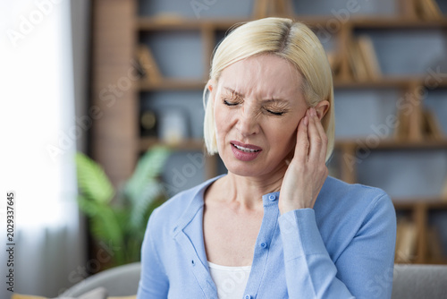 Canvastavla Mature woman suffering from an acute ear infection or earache, touching her pain