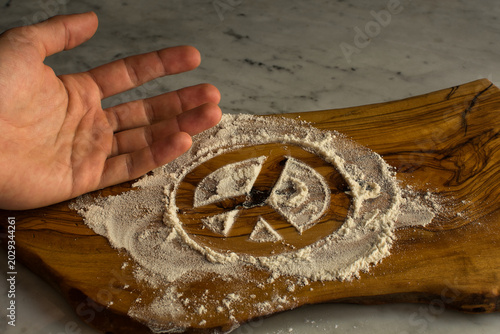 Foto Conceptual peace sign in flour on wood board with a human hand gesture