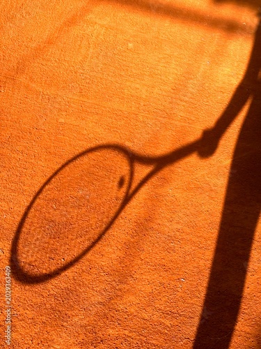 High angle view of a clay tennis court with net and warm sunset shadows