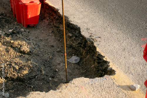 Close up of a deep square hole cut into an asphalt road for utility access
