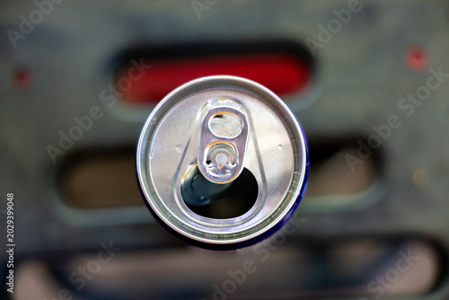Top view macro photograph open aluminum beverage can showing metallic pull tab sitting against dark blurred background invoking refreshing satisfying feeling for thirsty consumer