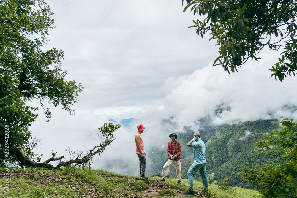 Ταπετσαρία Group of hikers standing on a grassy ridge overlooking misty mountain valleys at