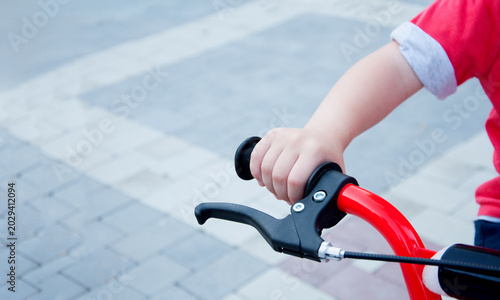 Child on a bicycle. Hand on the handlebars of a children's bicycle. Handbrake.