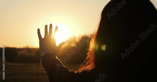 Silhouette of woman reaching hand toward sunset light. Concept of hope, inspiration and new beginning, emotional scene with warm sunlight and positive mood, horizontal video.