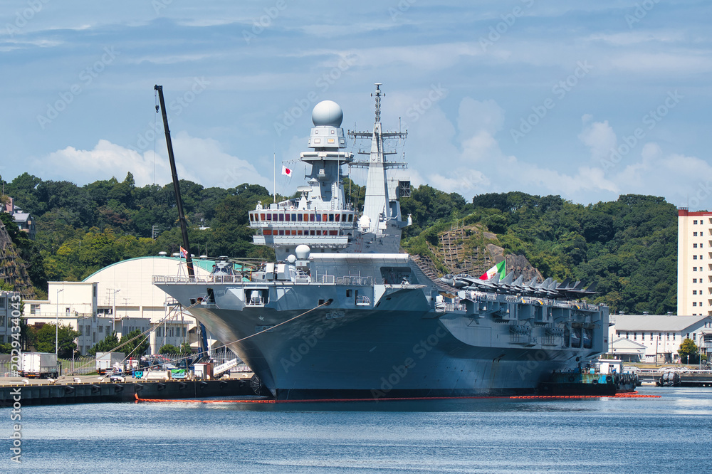 Obraz premium Large gray naval vessel moored at waterfront harbor in Japan