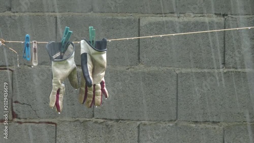 Working gloves hanging on a clothesline during rainstorm