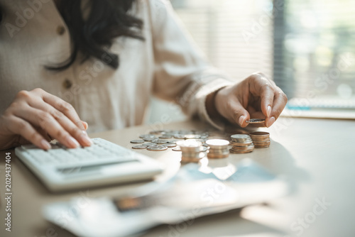 Woman counting coins beside calculator, showing emergency fund, savings cushion, personal finance, risk management, budget planning, and financial security concept.