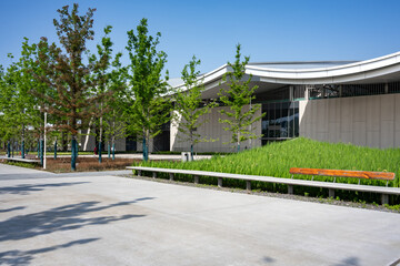 Modern building exterior with green lawn and trees under blue sky