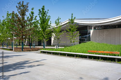Foto Modern building exterior with green lawn and trees under blue sky