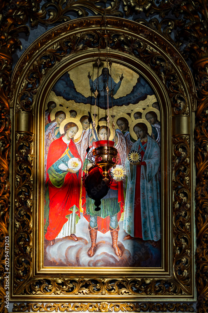 Fototapeta premium Orthodox christian icon of archangels in golden frame. Traditional religious painting of angels with a hanging oil lamp in church. Christian orthodox faith, spiritual art, cathedral interior concept