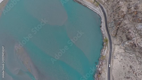 Cinematic nadir drone shot of a vehicle navigating the winding KKH in Northern Pakistan.