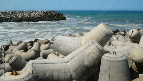 Foto Concrete Tetrapod Wave Breakers on Coastal Shoreline with Ocean Waves