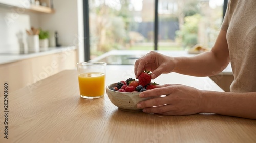 Hands picking fresh strawberry from a bowl of berries