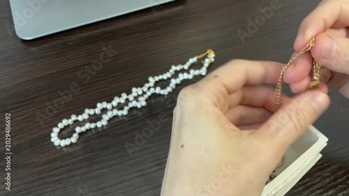 An attentive curator carefully inspects and displays jewelry pieces professionally. Expert hand separates and arranges sparkling precious jewelry with meticulous attention to detail