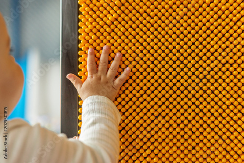 Bild auf Leinwand Baby hand touching yellow sensory wall in indoor playground
