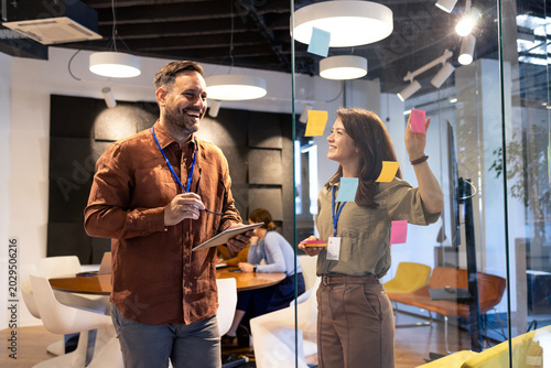 Business colleagues collaborating on creative ideas using sticky notes during a brainstorming session in a modern office