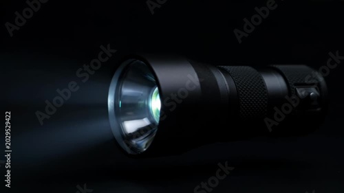 High-contrast handheld flashlight beams through dark night, illuminating the surroundings.