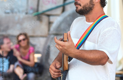 Street Musician Playing Electric Guitar with Rainbow Strap