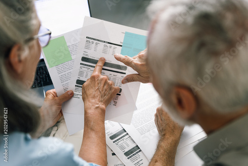 Senior couple analyzes utility bills and bank statements at home together