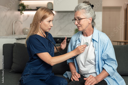 Obraz na płótnie Doctor checks heartbeat of elderly woman during home visit for chronic illness c