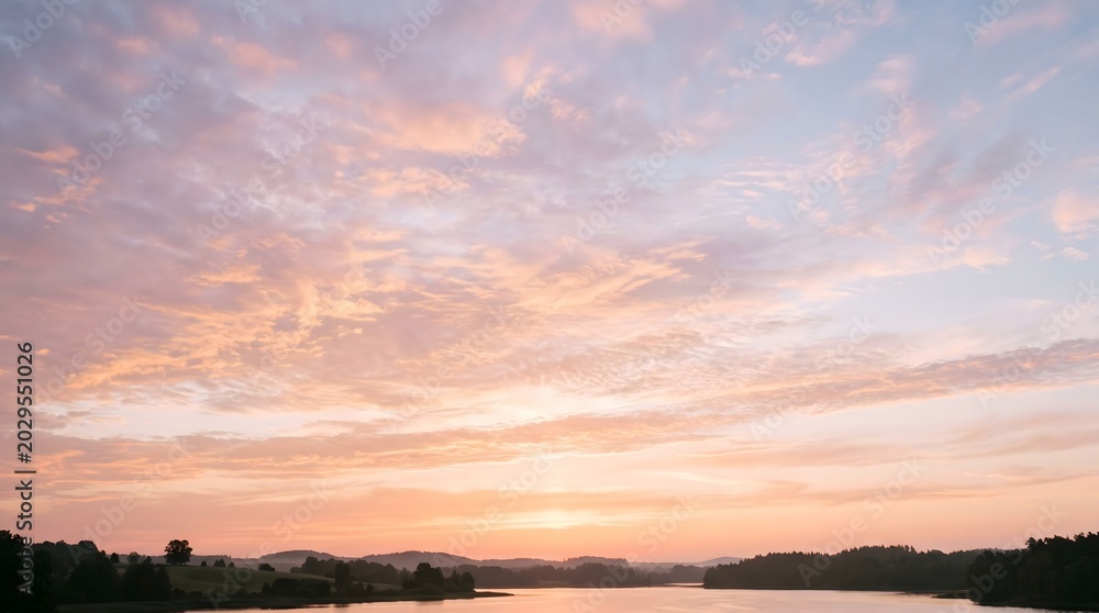 Fototapeta premium Pastel sunset clouds over tranquil lake and rolling hills
